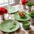 A cabbage leaf platter carries a smaller dip bowl nested among hand-painted peas and a garlic bulb, a classic majolica...