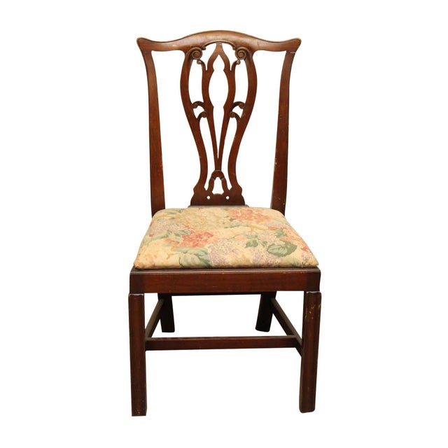 Ornate wooden back chair with a reupholstered light printed floral seat. The manufacturer and exact date of creation are...