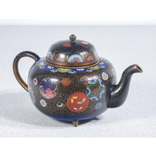 Cloisonné teapot and sugar bowl on a black background, with floral medallions and butterflies. Japan, early 20th century...