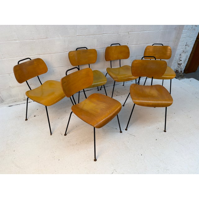 Set of six vintage dining chairs featuring molded plywood seats and backs paired with sleek metal frames. The sculpted...