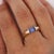 14K yellow gold ring features a 1.50 carat radiant cut tanzanite bar half bezel set between two round brilliant diamond...