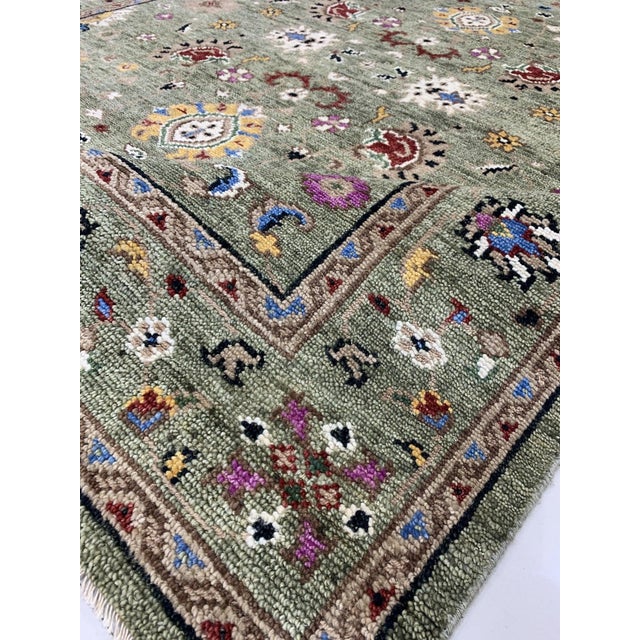An 8' x 10' hand-knotted wool rug with a soft sage green field of scattered Oushak-style blossoms in red, blue and ivory,...