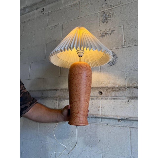 This charming ceramic table lamp features a textured orange base and pleated shade. The warm silhouette brings cozy...
