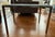 Description: Room & Board Parsons end table with a white opaque glass top and 1.5" brushed stainless steel legs. Clean and...