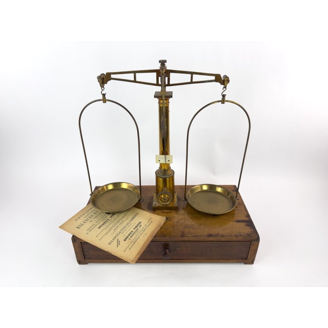 A finely crafted antique precision balance scale mounted on a wooden base with integrated drawer, produced by Gebr. Ott of...