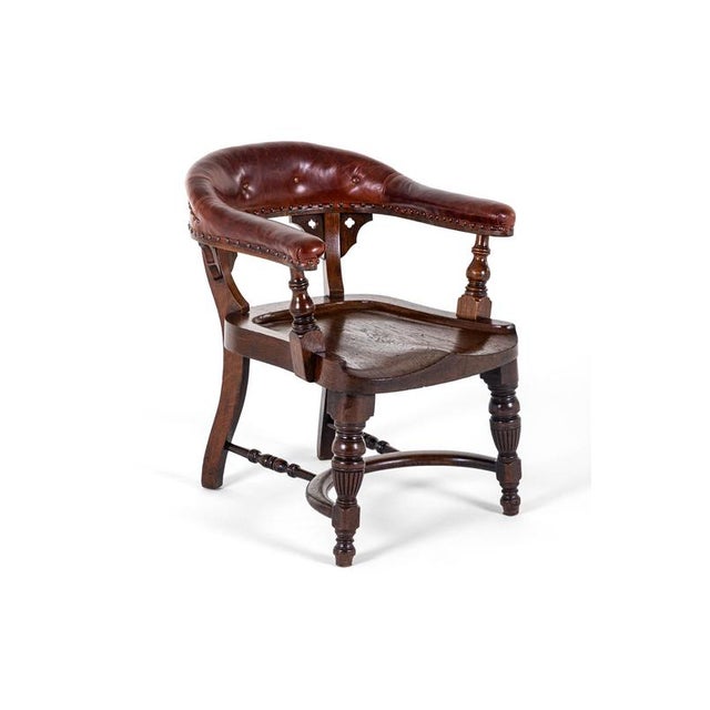 A large deep and wide ecclesiastical oak chair from a scottish church with open sides and wide welcoming arms. The...