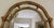 A vintage large arched framed rectangular gilded wall mirror by Carolina Mirror with a warm, gold tone finish, scalloped-...