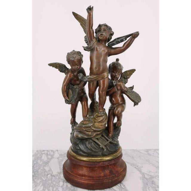 A trio of statues with a total of five angels on wooden bases. Bronze patina. The statues are made of metal from a zinc-...