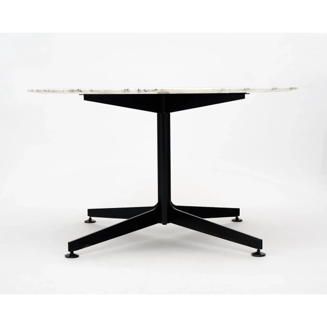 Round marble dining room table by Knoll with a black steel base supporting an intact, thick, veined Carrara slab....