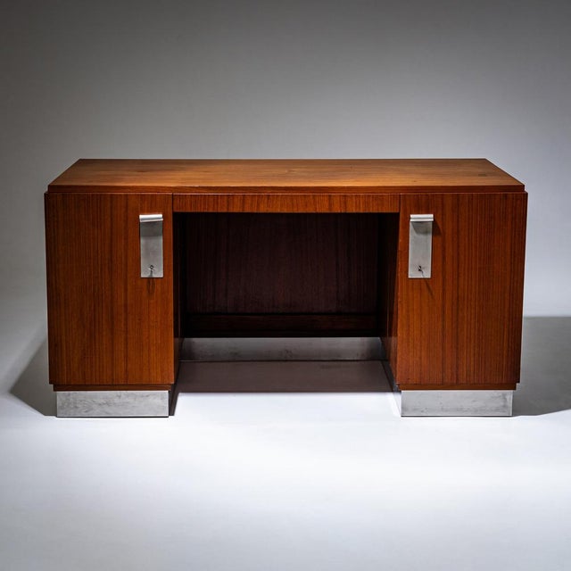 Large desk on a brushed metal base and lockable compartments on the sides. The handles are made of a smooth metal plates...