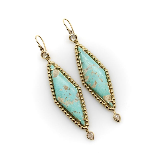 The elongated turquoise diamond-shaped tablet is the central focus of these earrings. The pale turquoise color has bits of...