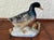 Glazed in blue, this porcelain duck figurine stands on the shoreline. The beak and feet are glazed in pale yellow and the...