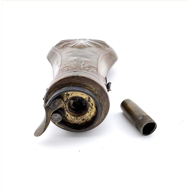 Antique 19th-century powder flask with a copper body, brass fittings, and embossed shell decoration to both sides. The...