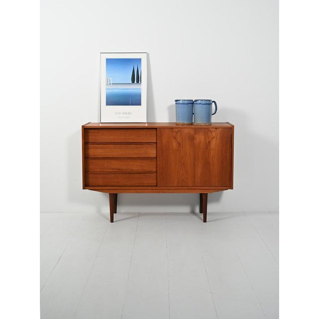 Compact teak sideboard with two compartments: sliding door with double offset shelf and column of drawers. Blade handles,...