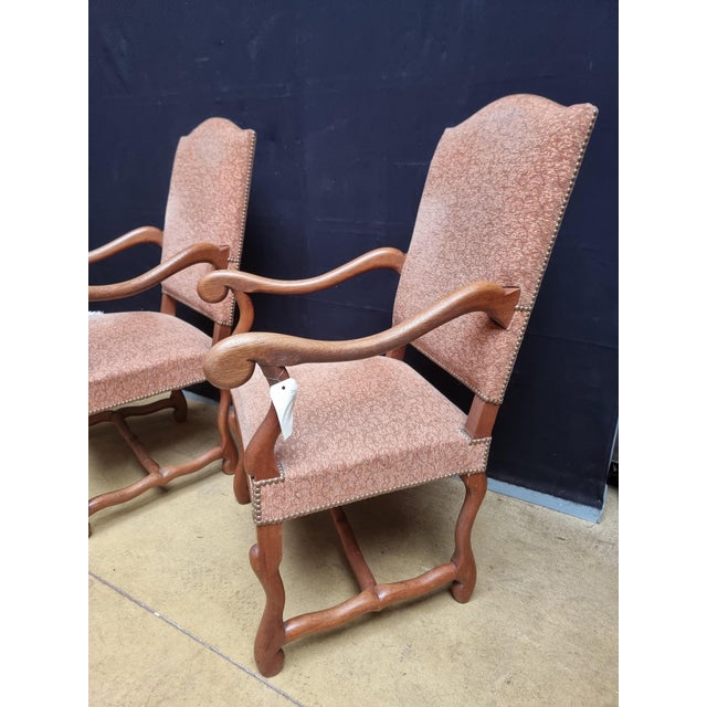 A pair of French Louis XIII style walnut os de mouton legs armchairs from the 20th century with large scrolling arms....