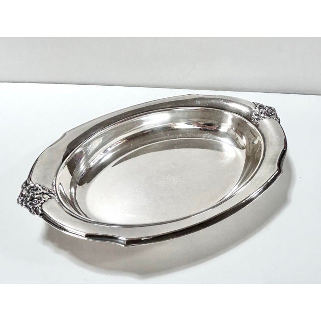 A classic vintage silver plate serving tray featuring sculptural floral handles, softly stepped edges, and elegant Art...