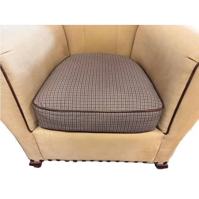 Handsome pair of equestrian-inspired club chairs featuring warm khaki upholstery accented with rich brown piping and...