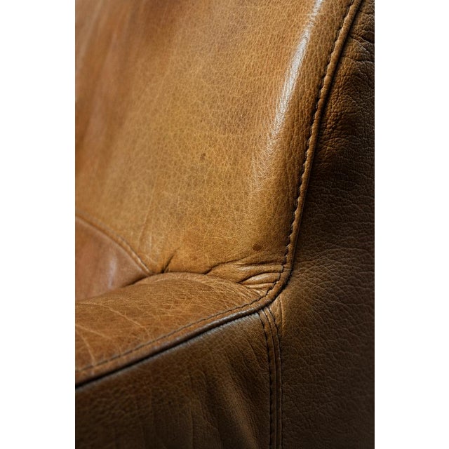 This three-seater leather sofa was manufactured during the 1960s. The upholstery is crafted from thick, genuine leather in...