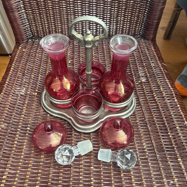 This item is an antique Victorian cranberry glass cruet set, typically used as a tabletop condiment caddy. These sets were...