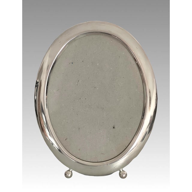 Simple and elegant silver plate on brass oval photo frame for a 5 x 7" picuture/photo. Rests on two small ball feet. Can...