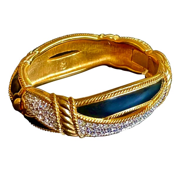 Chic clamper style bracelet made of gold plated metal embellished with glass crystals and enamel. Wonderful braided...