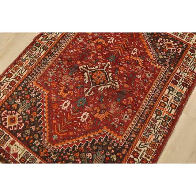 An authentic vintage tribal Shiraz rug hand-knotted with fine wool and natural dyes. This nomadic rug features a central...