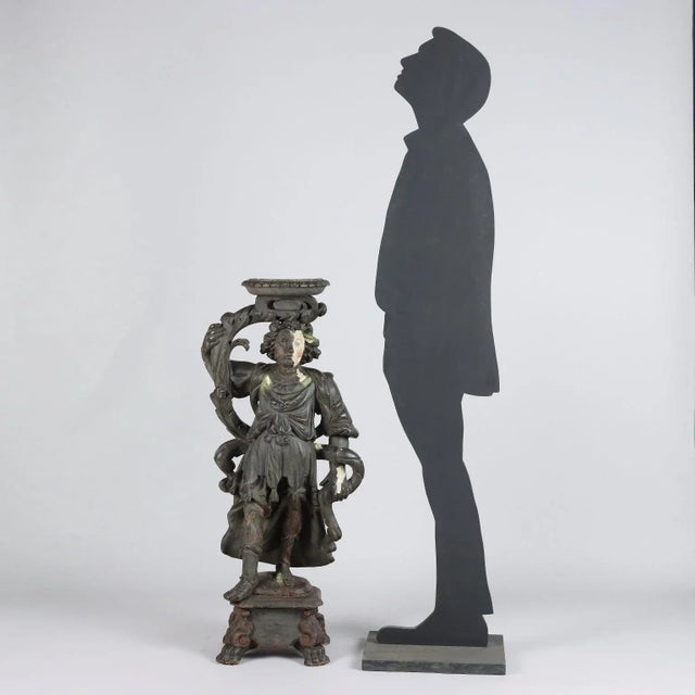 Sculpture of a baroque angel holding a vase in carved lime wood and completely repainted black in a later period,...