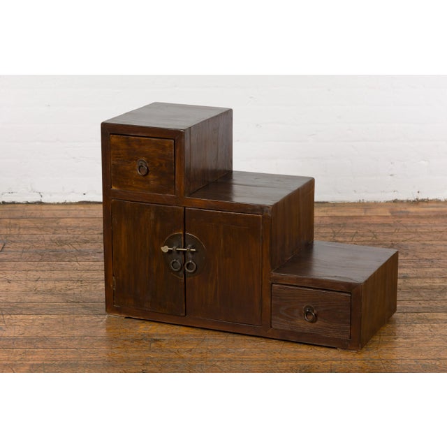 A Vintage Tansu Staircase Side Cabinet from the mid 20th century with two drawers and double doors on each side. Bask in...