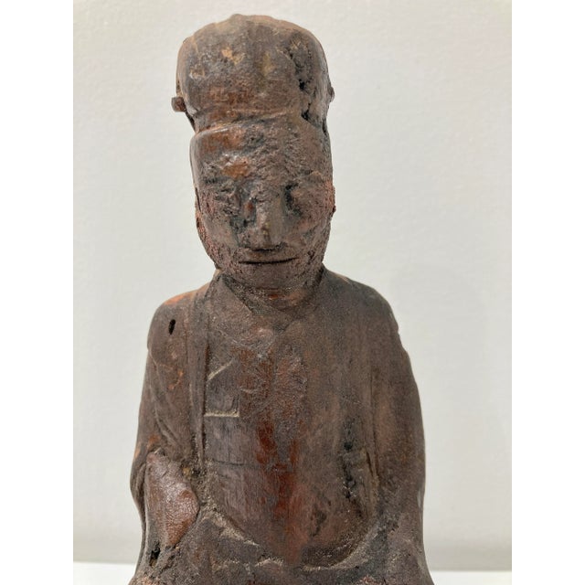 Very old solid wood statue depicts a Chinese ancestor figure. He wears typical Tao robe and hat. On the back of statue,...