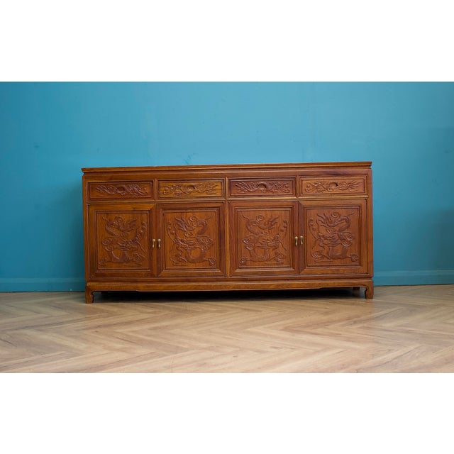 A large 1970s sideboard with carved dragon panels across the four cupboard doors and matching detail to the top drawers....