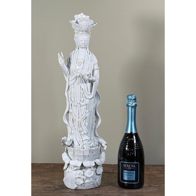 This tall Chinese blanc de Chine porcelain Guanyin figure is modeled with flowing robes, beaded jewelry, raised blessing...