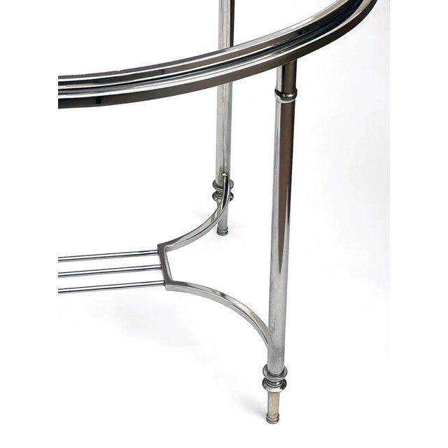 of neoclassical style, the oval inset beveled glass top within a nickel-plated frame; all raised on cylindrical supports...