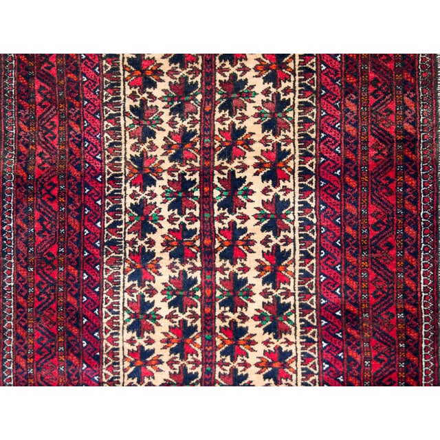 A beautiful mid-20th century Persian Baluch rug with a central stylized floral field surrounded by several petite...