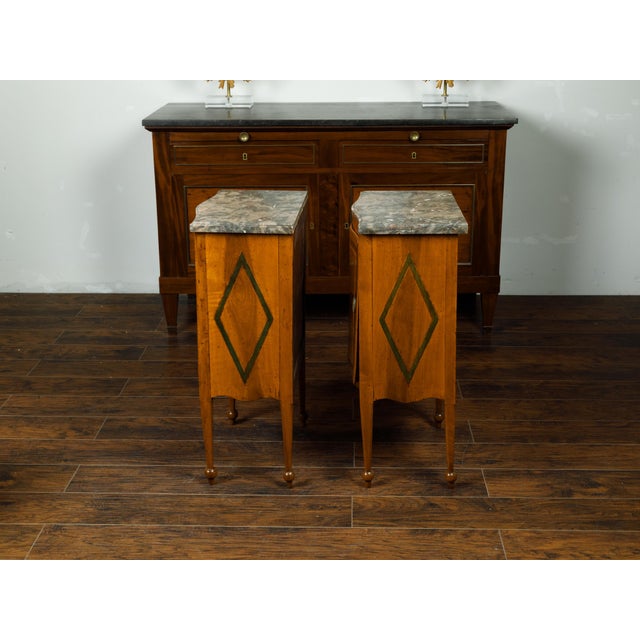 A pair of Italian walnut tables from the mid 19th century, with variegated marble top, single door and butterfly veneer....