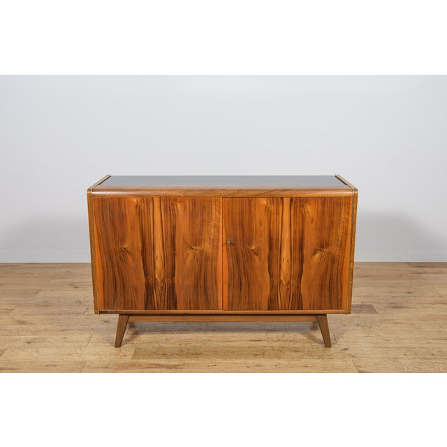 The small sideboard was designed by Bohumil Landsman and Hubert Nepozitek in the 1960s. It was manufactured by the Jitona...