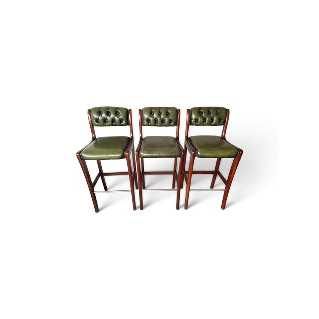 A set of three English Chesterfield-style bar stools featuring solid mahogany frames, olive green leather upholstery,...