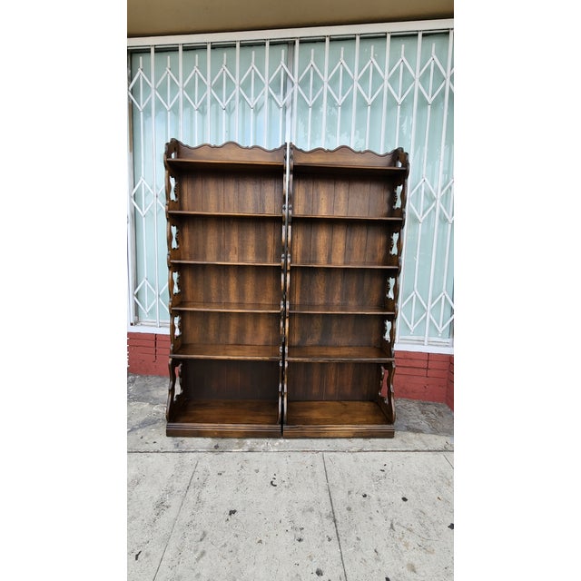 Sturdy pair of wooden bookcases with a dark brown finish. Each unit has five shelves and features decorative scalloped...