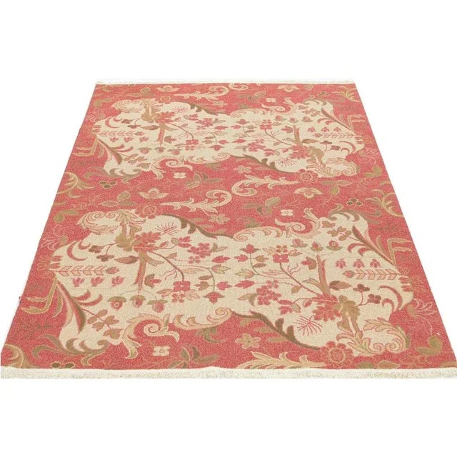 Handwoven Chinese area rug featuring a floral motif on a coral/terracotta colored field accented in shades of ivory,...