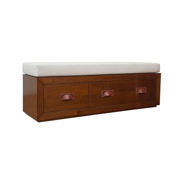 Storage bench on plinth base with leather pull hardware. Shown in medium walnut and upholstered in a natural linen fabric....