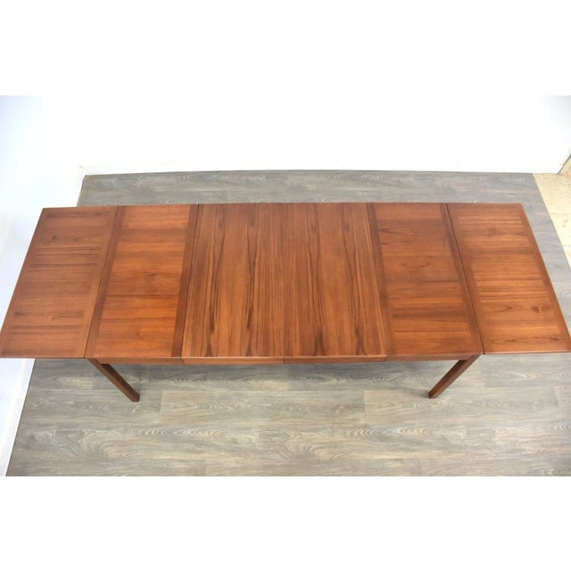 A mid century modern teak drop leaf table with two 18” leaves. Table fully extends to 107”. Each drop leaf is 17.75”....