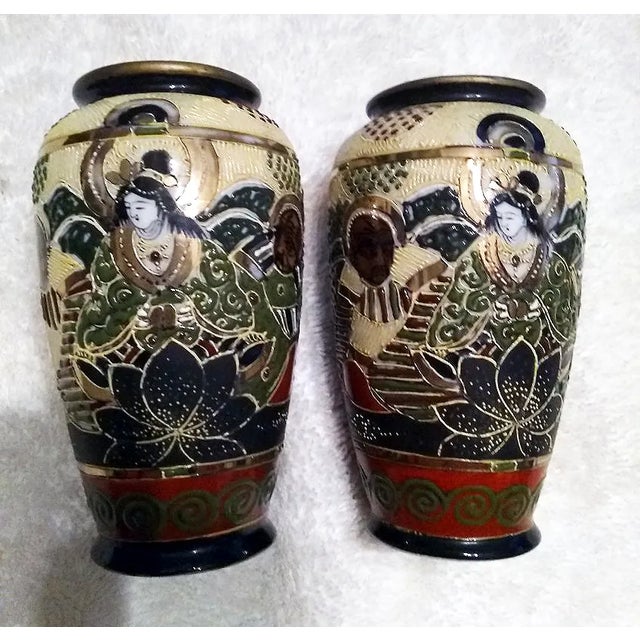 A striking mirrored pair of mid-century Japanese Satsuma-style porcelain cabinet vases, featuring intricate hand-painted...
