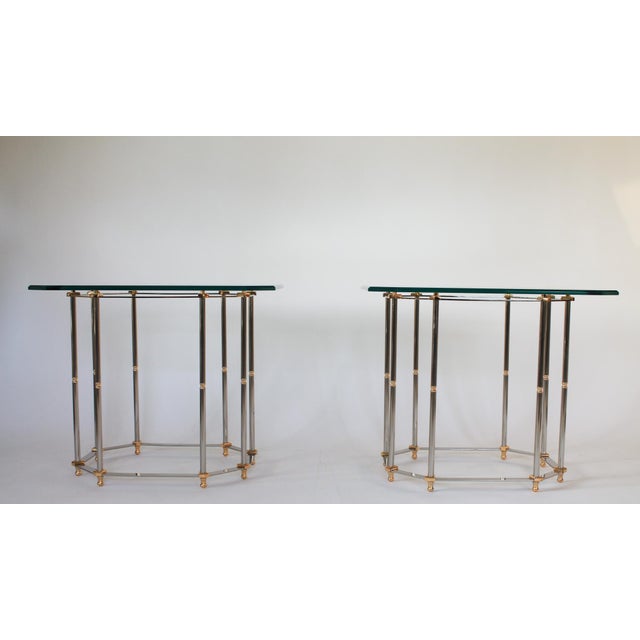 Vintage Hollywood Regency style brass and chrome plated side or end tables. Each features thick glass top and eight legs...