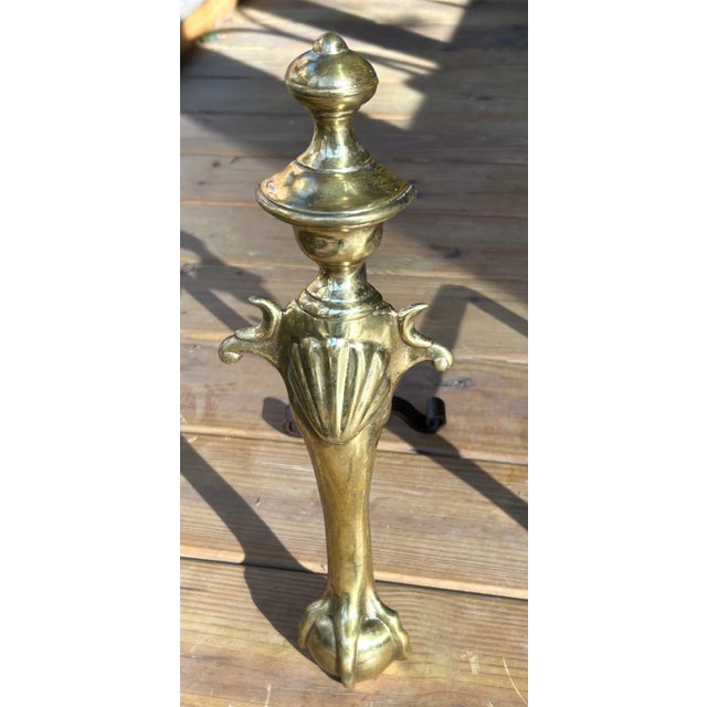 Offering an attractive set of brass andirons featuring a shell embossed emblem and detailed ball and claw feet.