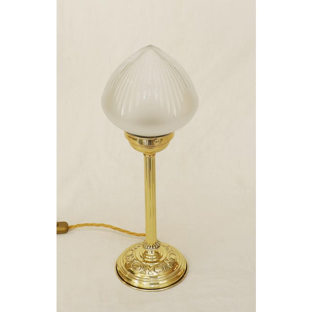 Pair of Art Nouveau floor lamps Two brass table lamps, circa 1915. Geometrically embossed base. Chased column. Frosted...