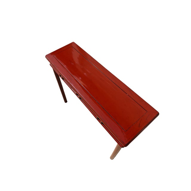 This a contemporary, slender console table features a vibrant, high-gloss red lacquer finish. The design includes a flush...