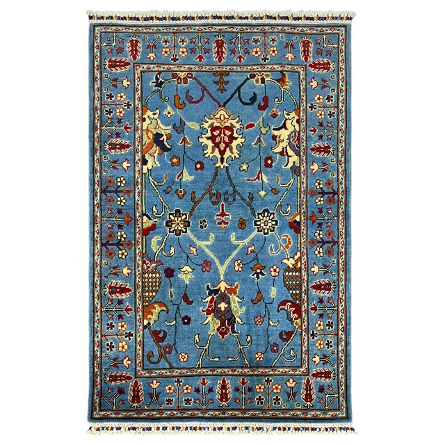 This Sultani Persian style rug has a clear blue field with curved vines, flowers, and leaves in cream, burgundy, rust, and...