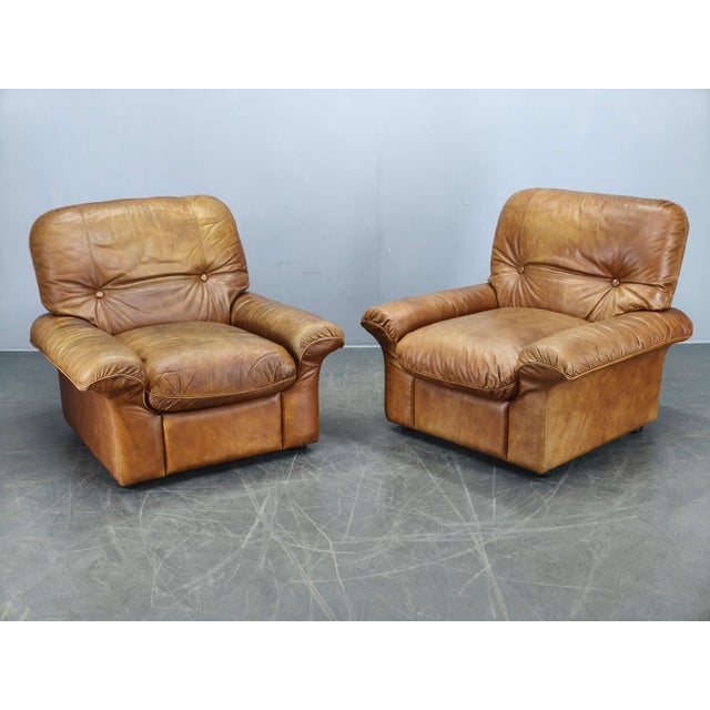 Elegant pair of Italian lounge armchairs produced by Arcon Italia during the 1970s. Crafted from high-quality cognac...