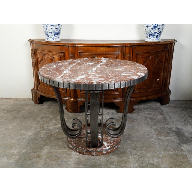 A French Art Deco period center table from the early 20th century in the manner of Raymond Subes, with steel scrolling...