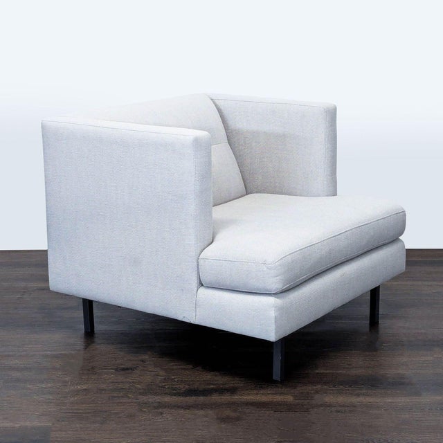 This CB2 lounge chair features a clean, modern design with soft light gray upholstery and sleek metal legs. Its deep seat...