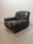 Striking black leather lounge chair with distinctive lace detailing at the corners and brass buttons on the back....
